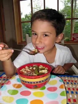 A young boy enjoying a bowl of pasta