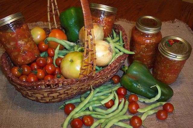 Basket of fresh garden vegetables beside home-canned jars